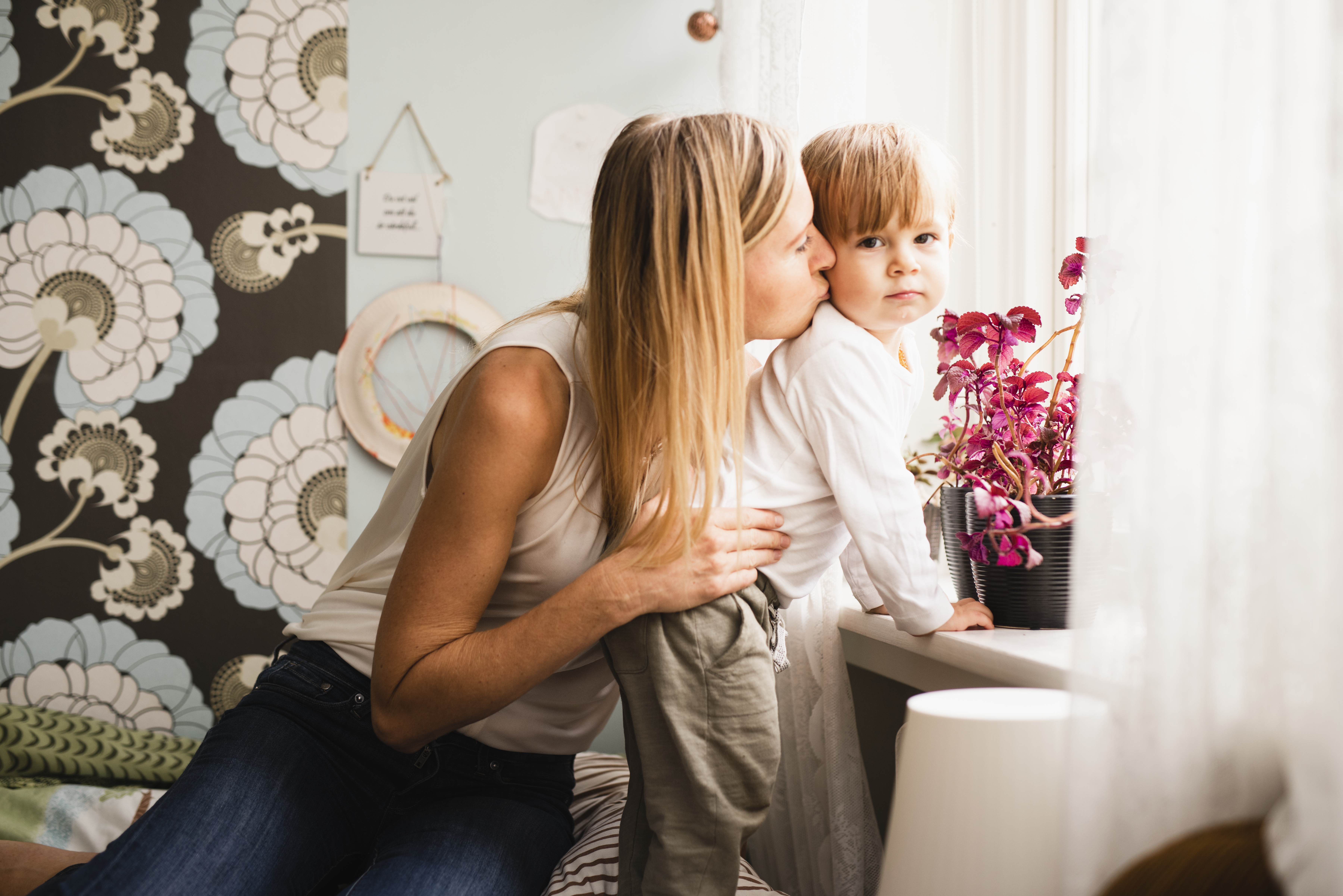 Mamma med son sitter vid fönstret i lägenheten.