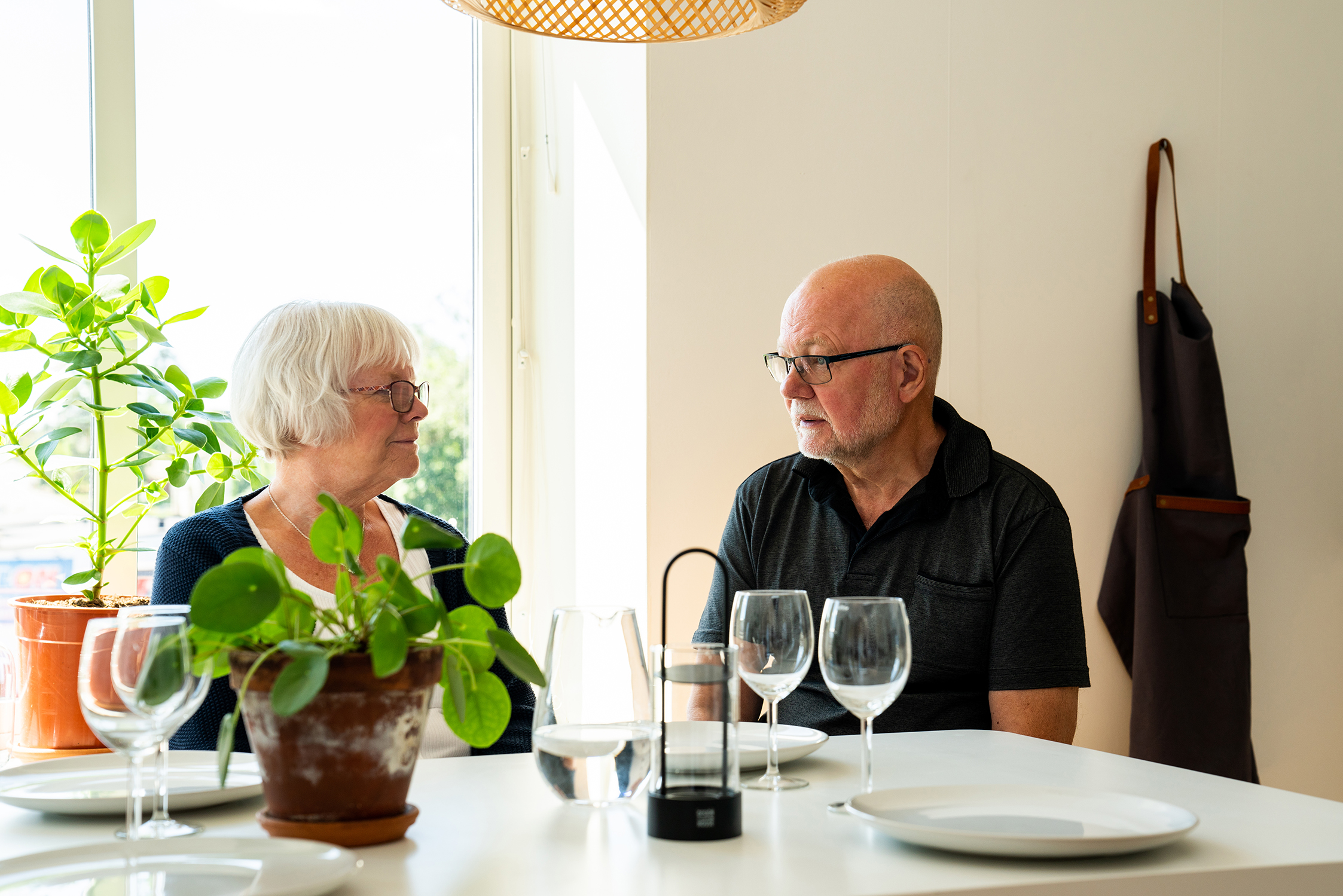 Äldre par samtalar vid köksbord
